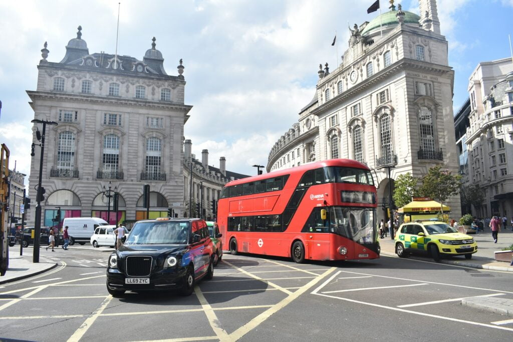 a red double decker bus driving down a street